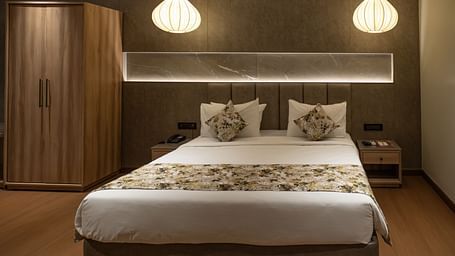 a double bed with lamps above and a wardrobe inside the suite - The Cindrella Hotel, Siliguri