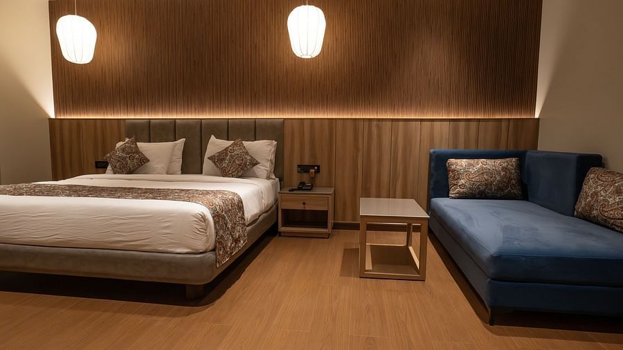 A double bed with a lounger next to it inside super deluxe room - The Cindrella Hotel, Siliguri