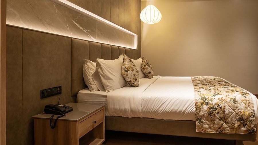 A double bed with a side table inside the suite - The Cindrella Hotel, Siliguri