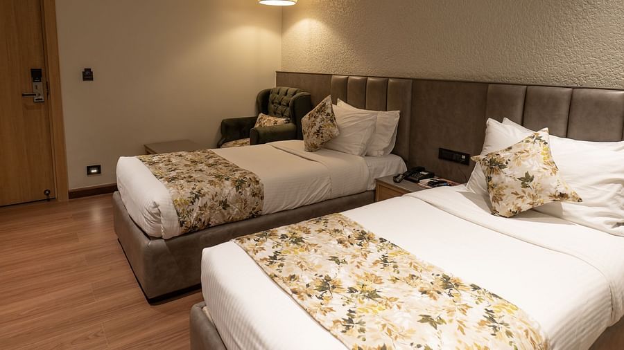twin beds with lamps above them inside the deluxe room - The Cindrella Hotel, Siliguri