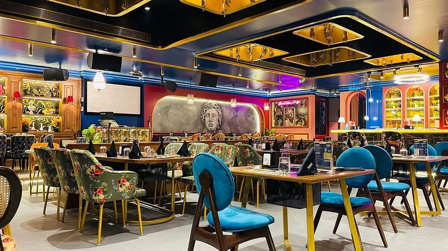 An image of a restaurant Themis Barbecue House NSP Pitampura featuring wooden chairs and tables with glass shelves that has food it in