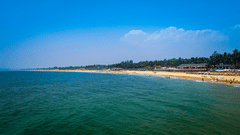 Beach scene with calm water and people enjoying the sun in Candolim, Goa.