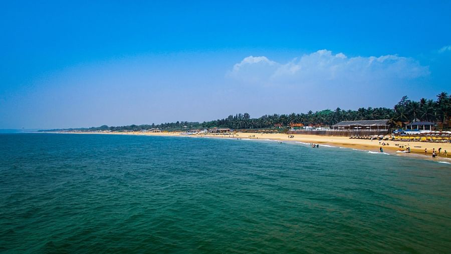 Beach scene with calm water and people enjoying the sun in Candolim, Goa.