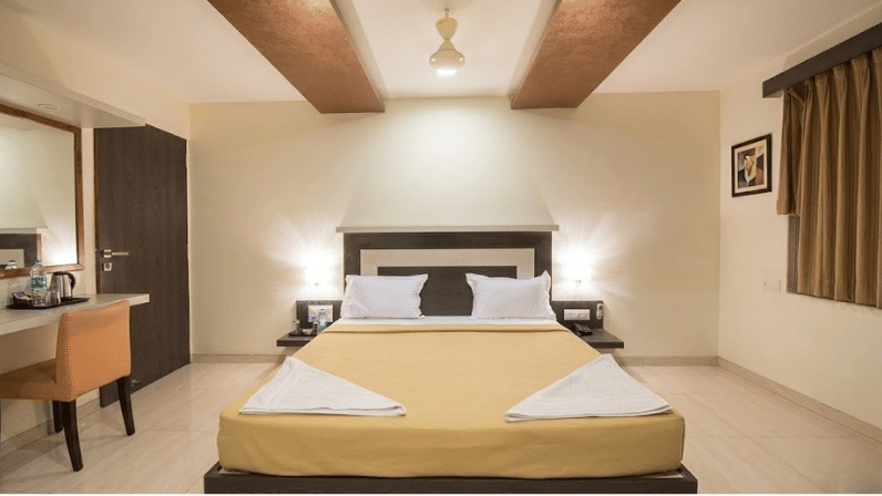 Minimalist and modern executive bedroom featuring a double bed with beige linens and overhead wooden panels.