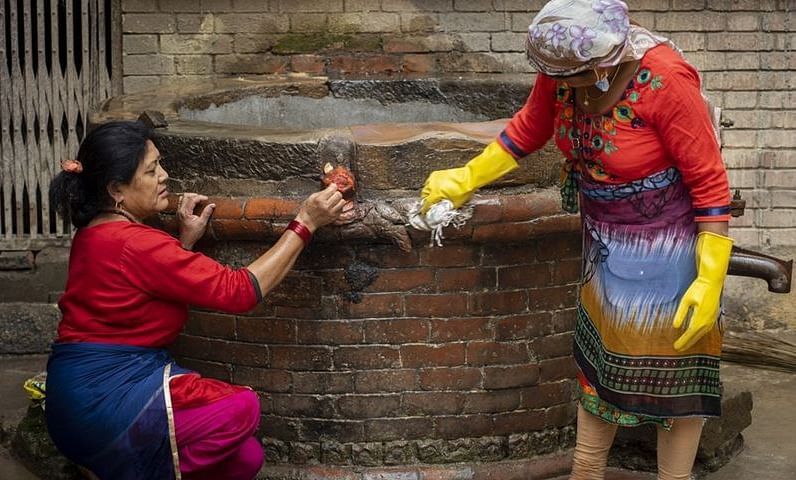 Two women seen cleaning a well