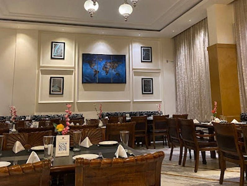 Full view shot of the Gold Plate restaurant with several photo frames wall mounted behind the dining tablesCorner view shot of the dining area of the Gold Plate restaurant with central air-conditioning and a small cabinet in the corner of the restaurant - 