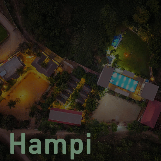 Nature Trails Ashoka Resort Hampi hotel card with aerial night view of illuminated resort buildings and pool in Hampi