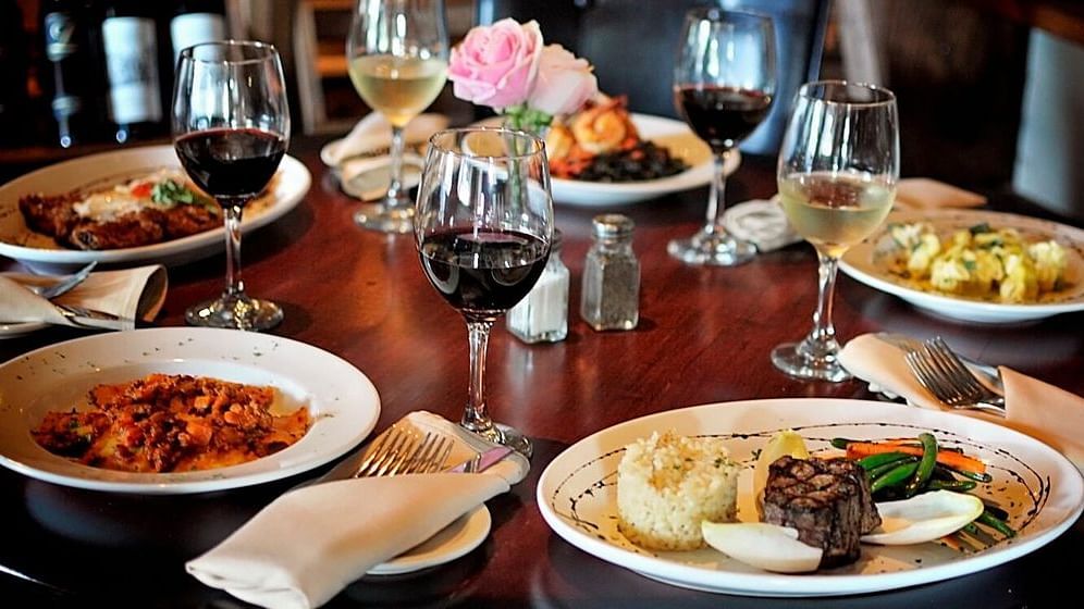 A beautifully set dining table with multiple courses, wine glasses, and napkins, suggesting a formal meal.