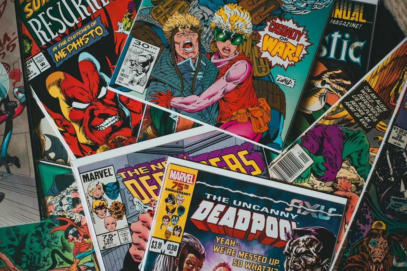 A collection of assorted comic books overlapping each other. Visible titles include Deadpool and other superhero-themed comics, featuring colorful illustrations and dynamic characters on the covers.
