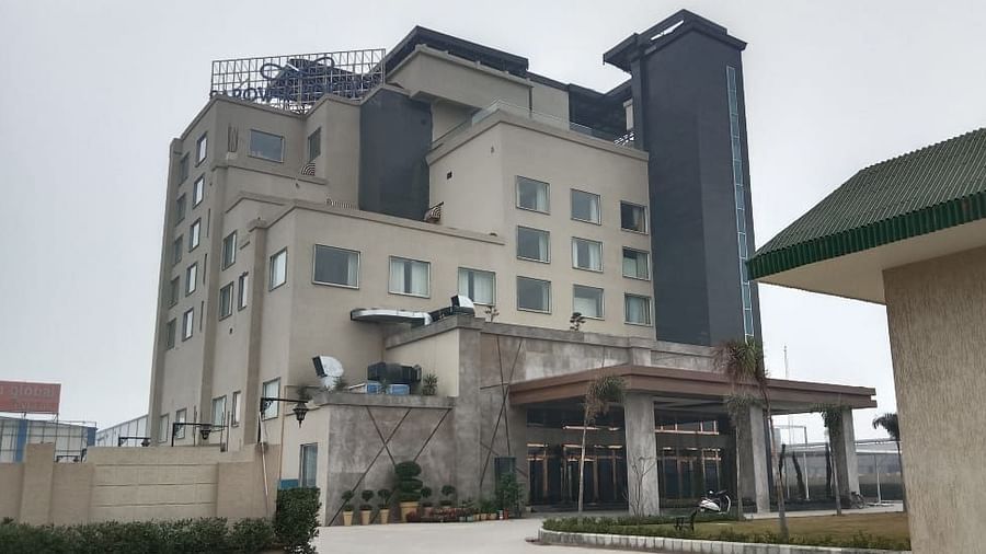 Facade of the hotel coloured in grey with a garden in front of the building - Sarovar Portico Sonipat