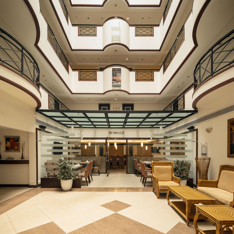 Pavilion at The Residency Karur features a patterned floor, seating areas, and glass-enclosed spaces under a skylight.
