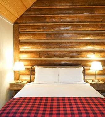 A room with a double bed and side tables with night lamps placed on it -Shaver Lake Village Hotel.