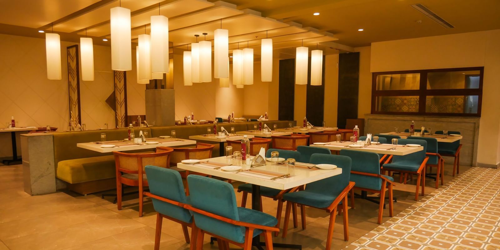 A brightly lit restaurant interior with tables set for dining and a buffet counter in the background at Shilton Dee Cee.