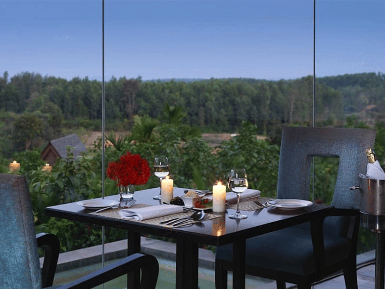A table for 2 set against a scenic view of the nature at Odyssey Restaurant at The Serai Chikmagalur