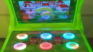 Bright green panda-themed arcade gaming machine with glowing buttons and a screen display at Vedic Village Spa Resort kids activity area.