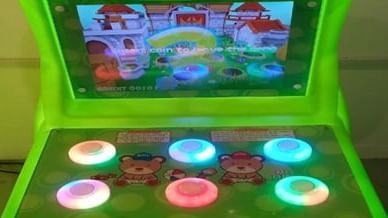 A bright green arcade game machine featuring a frog character and colourful buttons