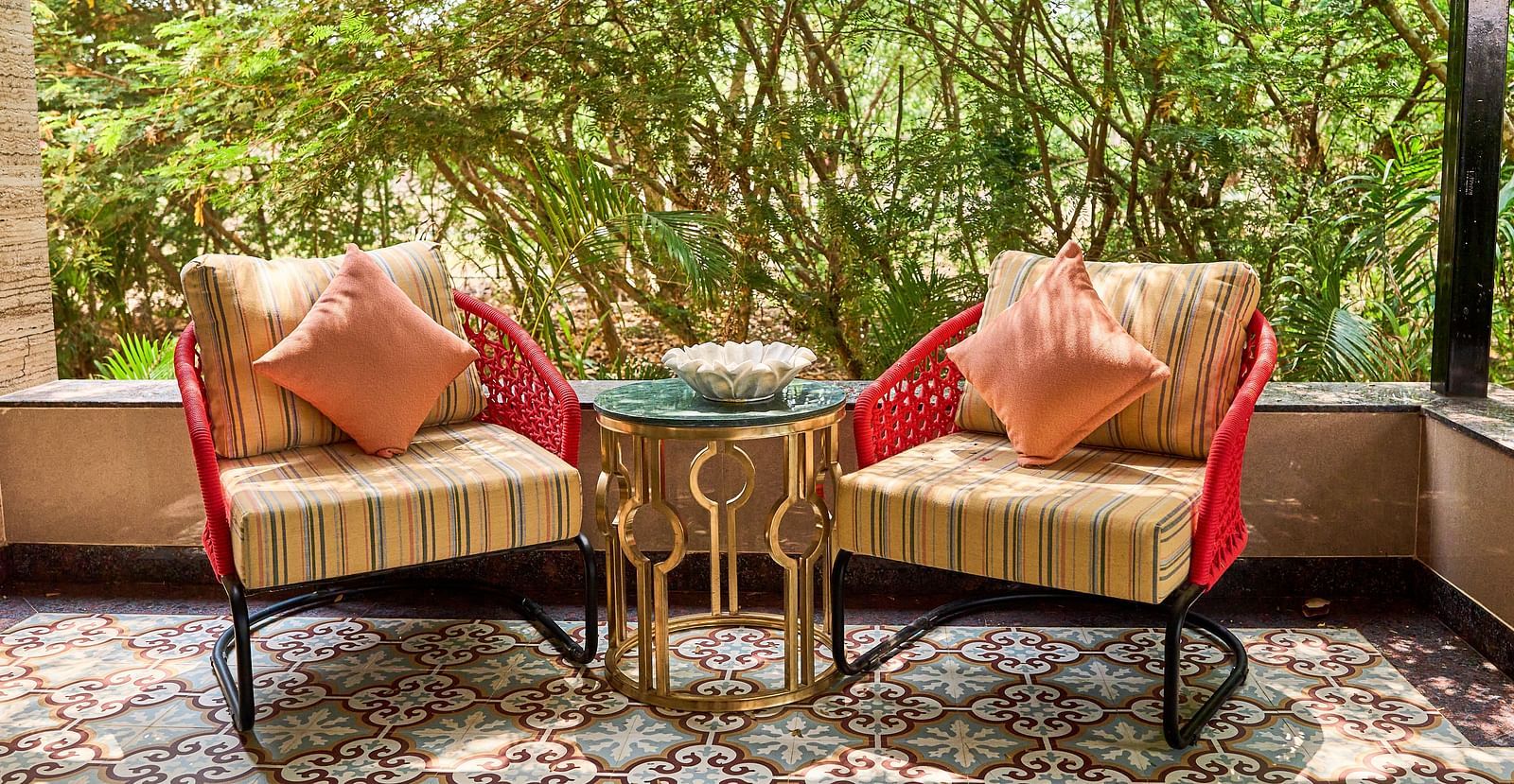 Two chairs placed beside the mini table, with lush trees as a backdrop at Mayfair Manor, Alibag