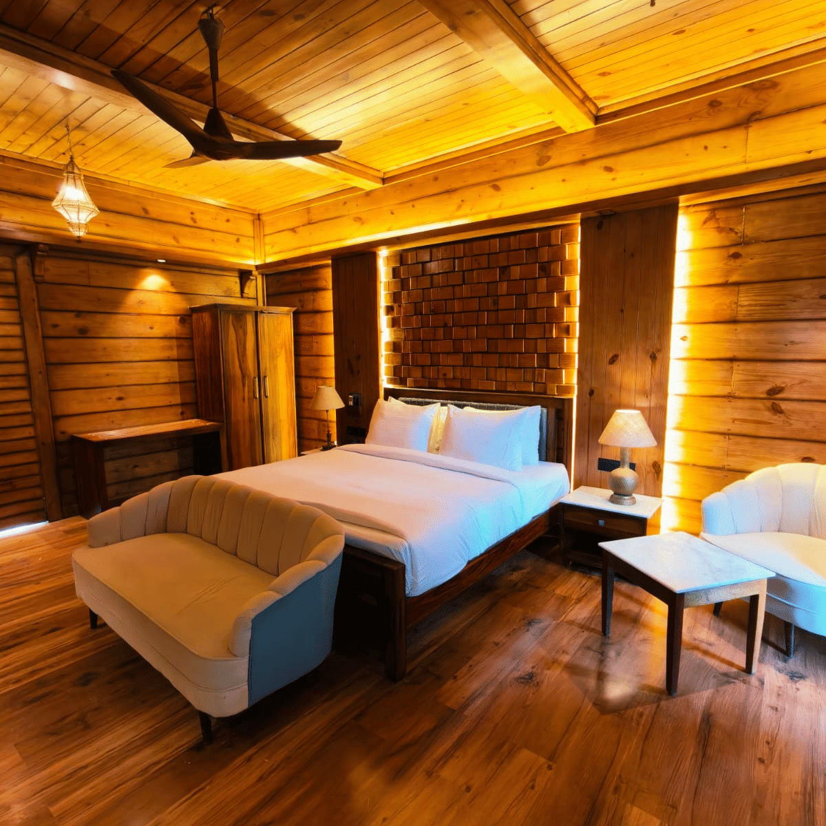 A bedroom at The Baagh Ananta Elite, Ranthambore featuring a king size bed, upholstered bench, single sofa, and small coffee table.  