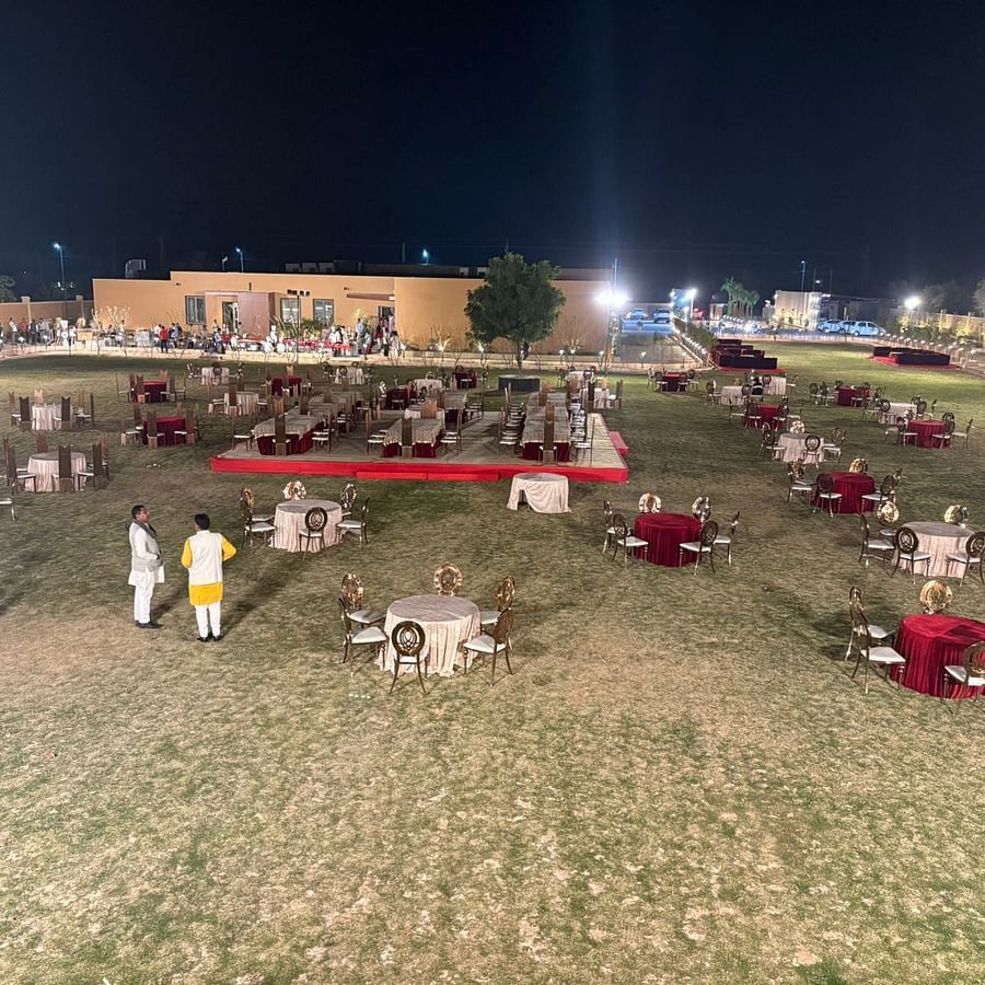 An image of a outdoor banquet hall featuring several sets of tables and chairs and a stage set up at the centre - Pride Hotels Group
