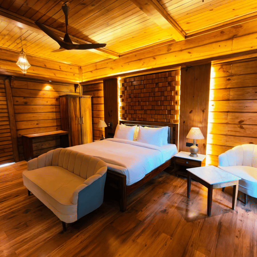 A bedroom at The Baagh Ananta Elite, Ranthambore featuring a king size bed, upholstered bench, single sofa, and small coffee table.  