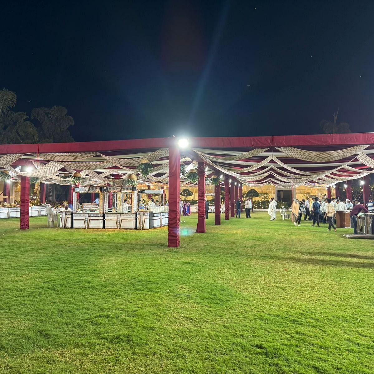 an outdoor banquet area at Lords Hrim Akshara Resort Basar decorated with red canopy, and several counters located at different spots