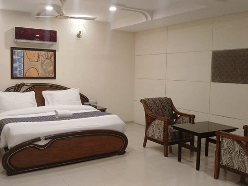 Suite Rooms at VITS Select, Bharuch featuring a double size bed, a bedside table, and a seating area with chairs and centre table.
