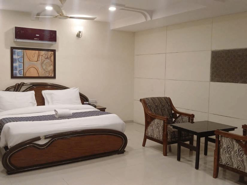 Suite Rooms at VITS Select, Bharuch featuring a double size bed, a bedside table, and a seating area with chairs and centre table.