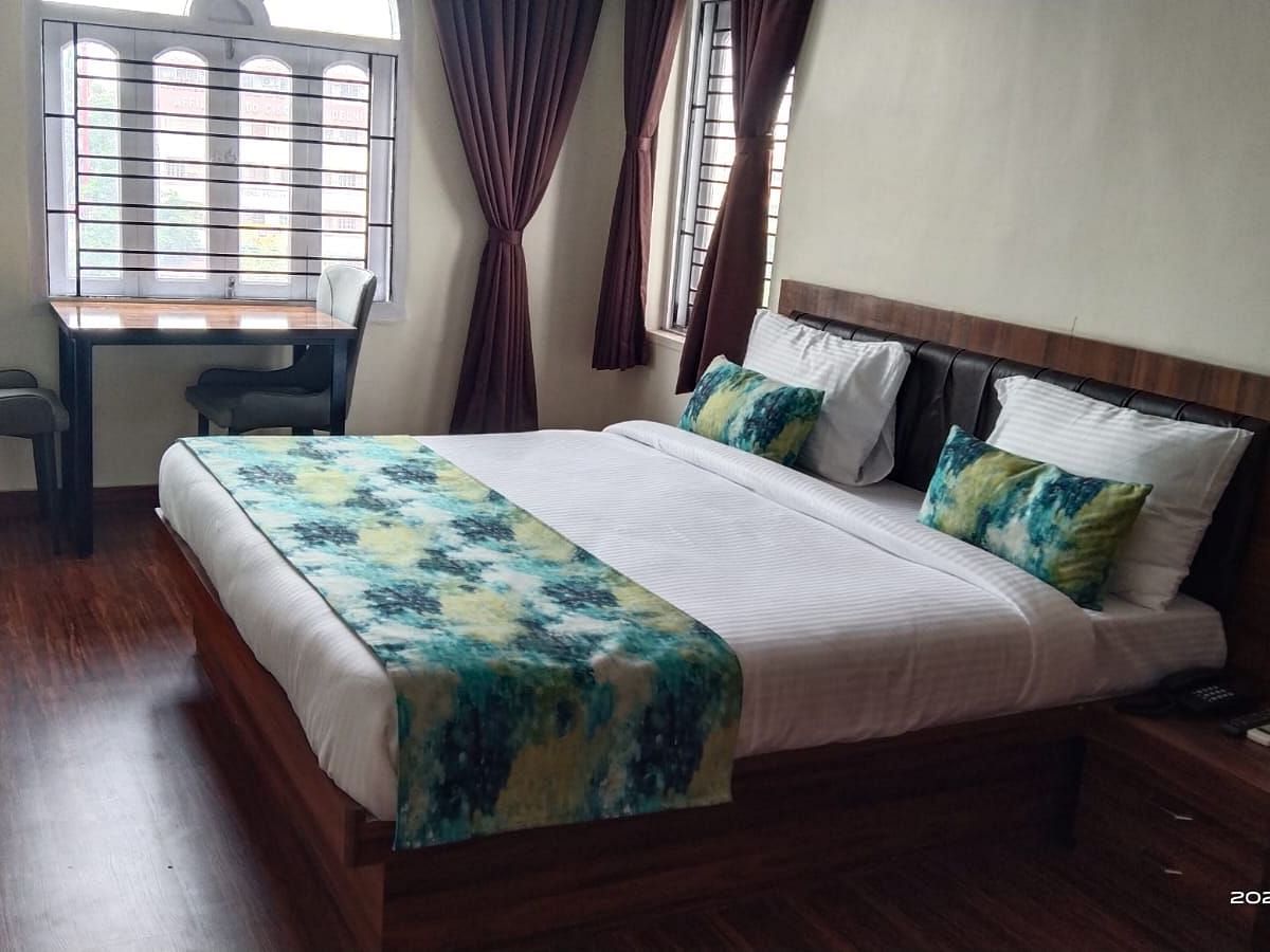 A double bed with chairs & study table next to it inside Premium room with balcony - Ecotel Kolkata