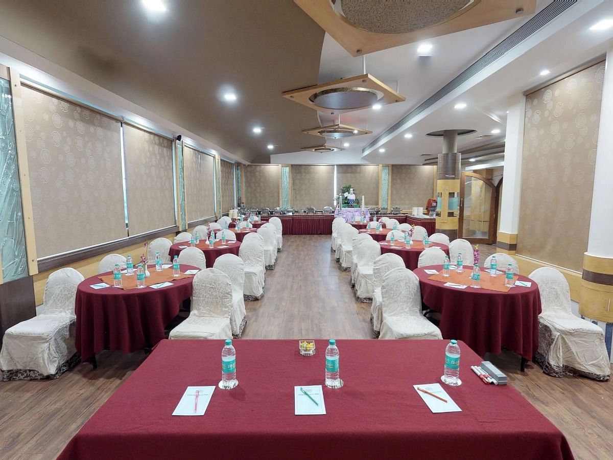 View from the stage of a well lit conference hall setup with designated tables and chairs