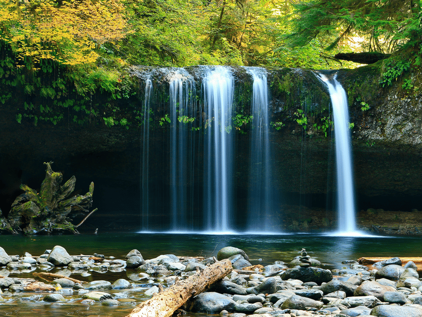 A waterfall cascading down to a waterbody with rock and nature surrounding it