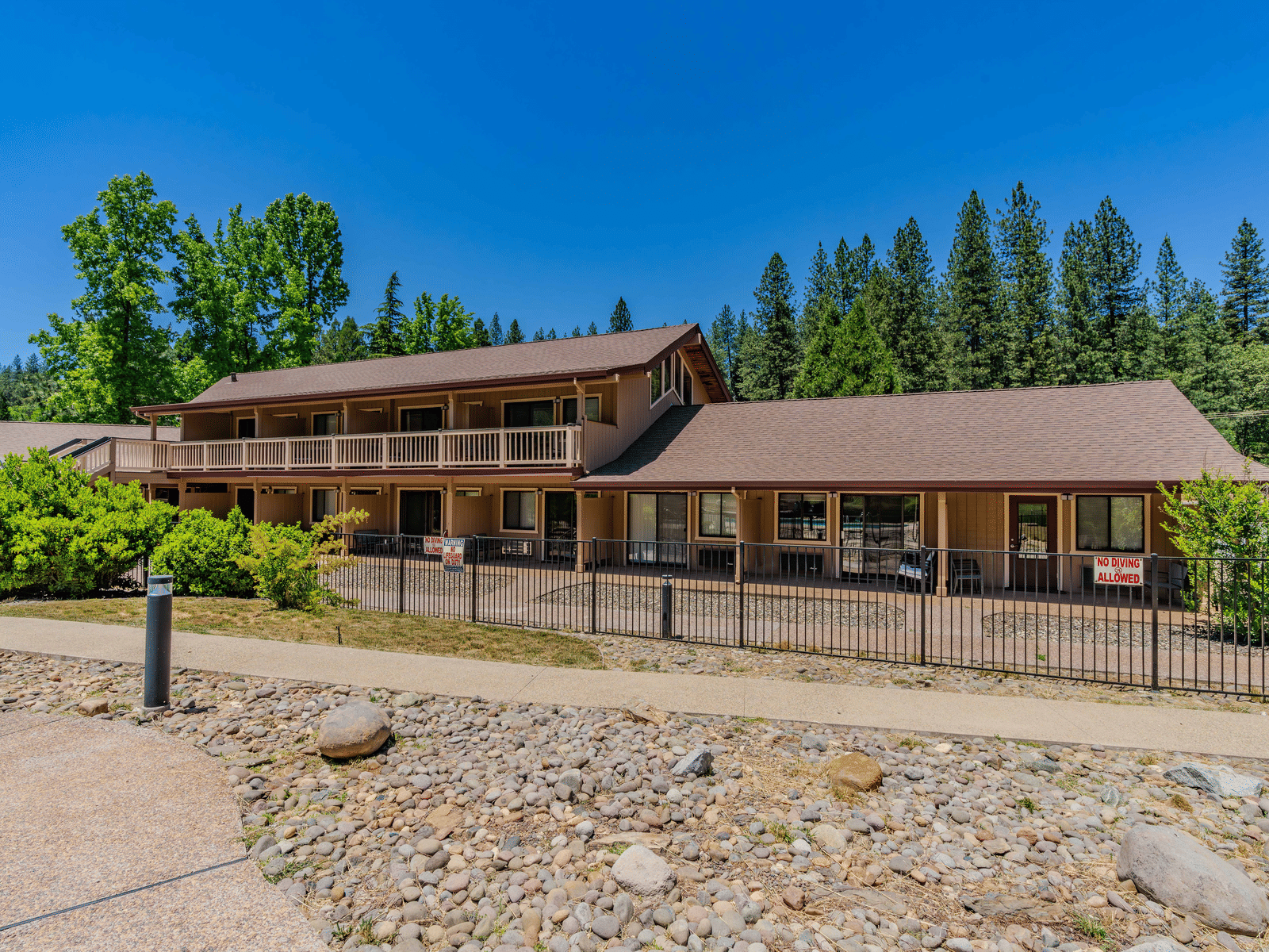 A view of a cabin at Amador Hotel with a forest in the backdrop on a clear, blue day.