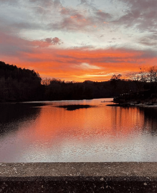 a beautiful sunset with hues of orange and sky blue over a pristine lake