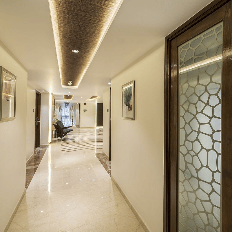 Long, well-lit corridor with warm lighting, marble floors, and modern room doors - The Citrine