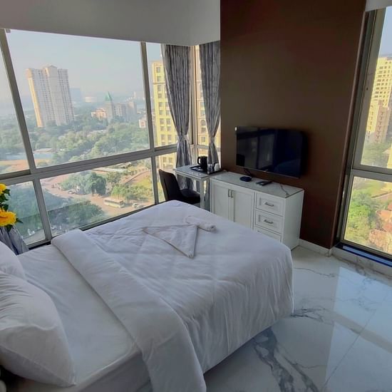 deluxe room at Maxxvalue Hotel, Chitranjan Tower, Powai with a posh bed and white linens along with floor-to-ceiling windows offering ciy view3
