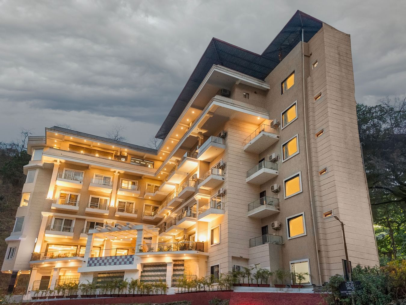 Facade of Stone Wood Hotel, Rishikesh with a cloudy sky in the background.