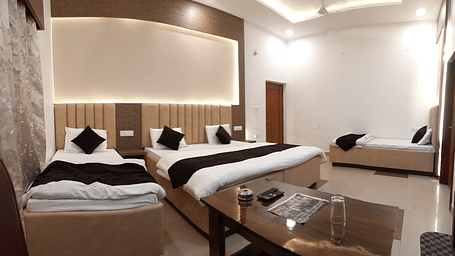 A hotel room in Roorkee with bright lights, a king size bed, two single beds and a teapoy - Motel Divine International, Roorkee