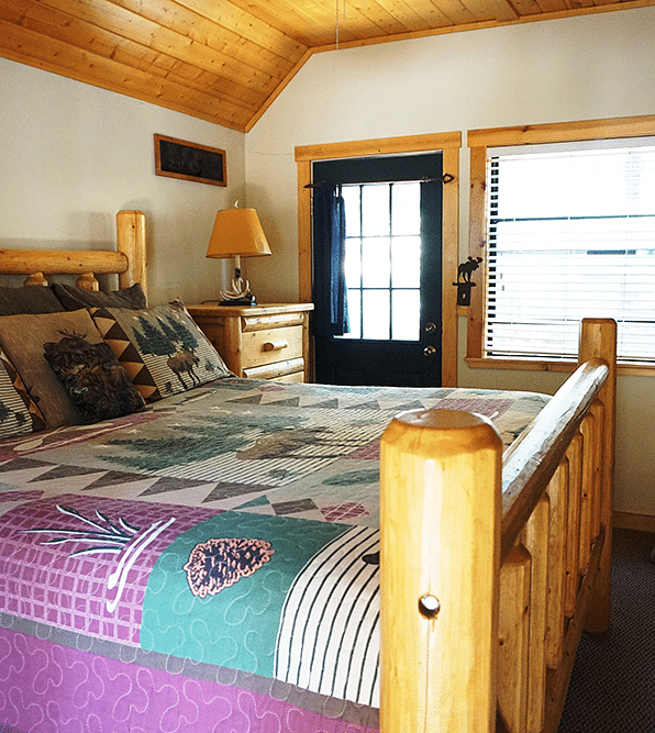 A room with a double bed and wooden paneling on the ceiling at Shaver Lake Village Hotel.