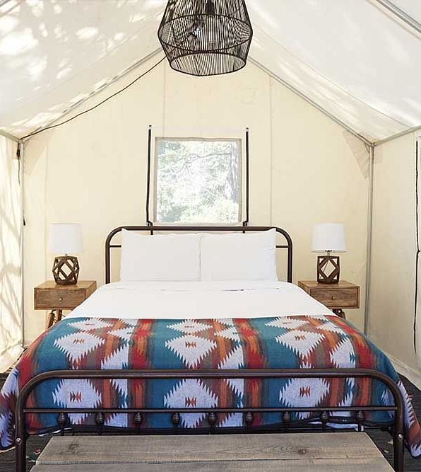 A tent with zip-down windows and a double bed placed in the middle at Shaver Lake Village Hotel.