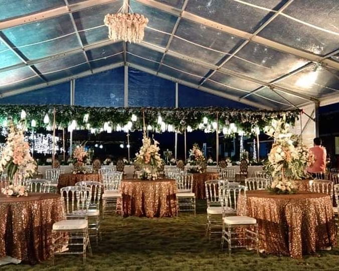 Grandly decorated event space of GK Hill View Resort featuring round seating tables, overhead shed, ample lighting and decorations.