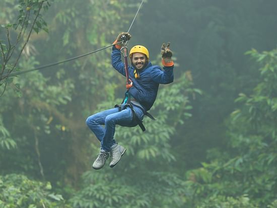 a person doing zip lining with greenery in the background - Stone Wood Jungle Resort, Dandeli