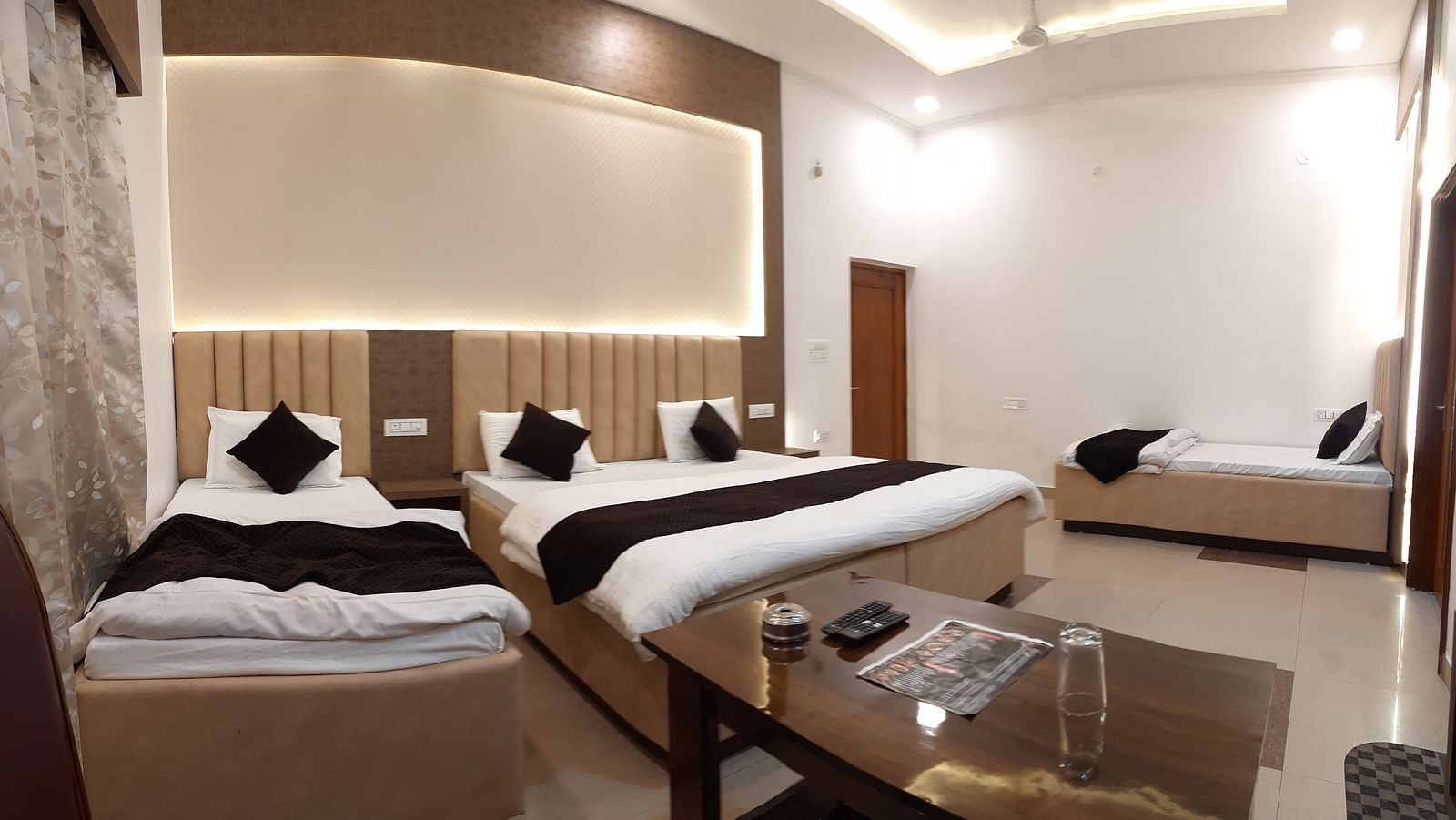 A hotel room in Roorkee with bright lights, a king size bed, two single beds and a teapoy - Motel Divine International, Roorkee