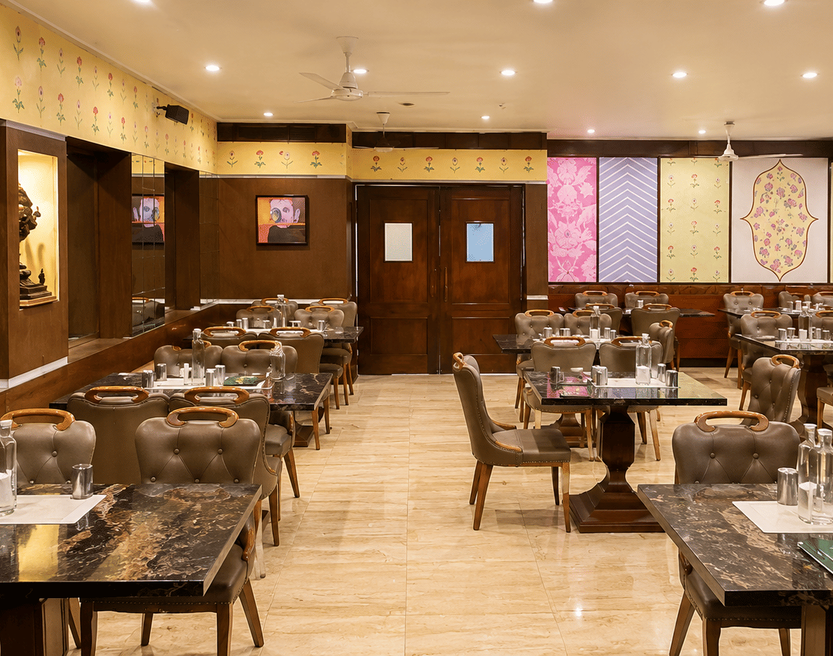 Super Snax restaurant with granite-topped tables, upholstered chairs, floral wall motifs, patterned panels and a tiled floor at MAYFAIR Garden, Rourkela.