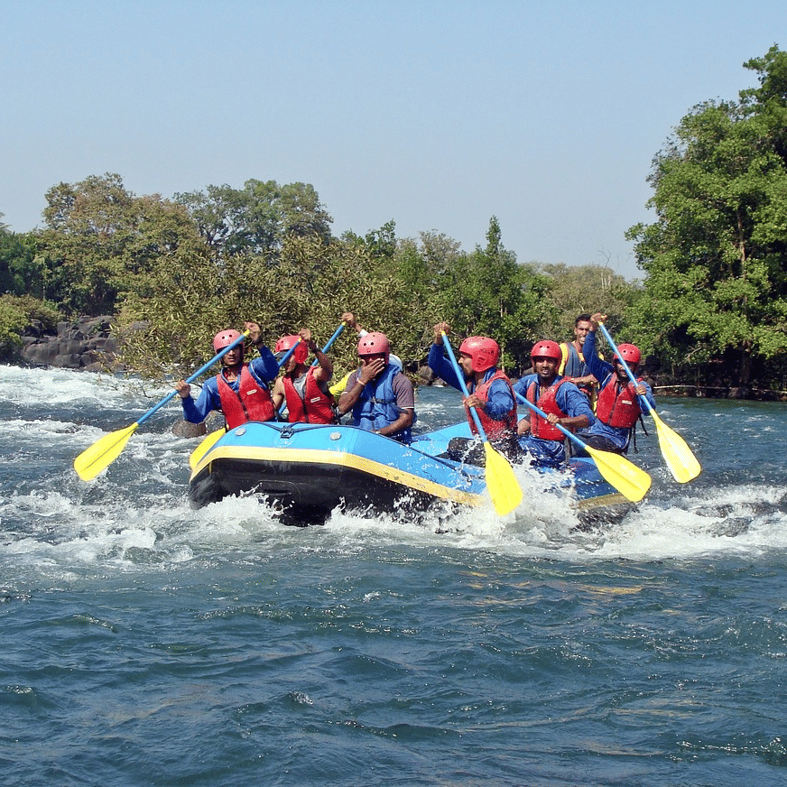 A group of adventurers in life jackets, joyfully rowing together in their raft on a scenic river, surrounded by nature.