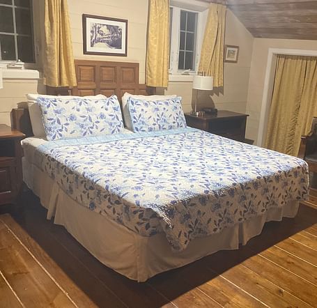 Bedroom with a bed, wooden floor, wooden furnishings, and beige walls | A Stone's Throw Away