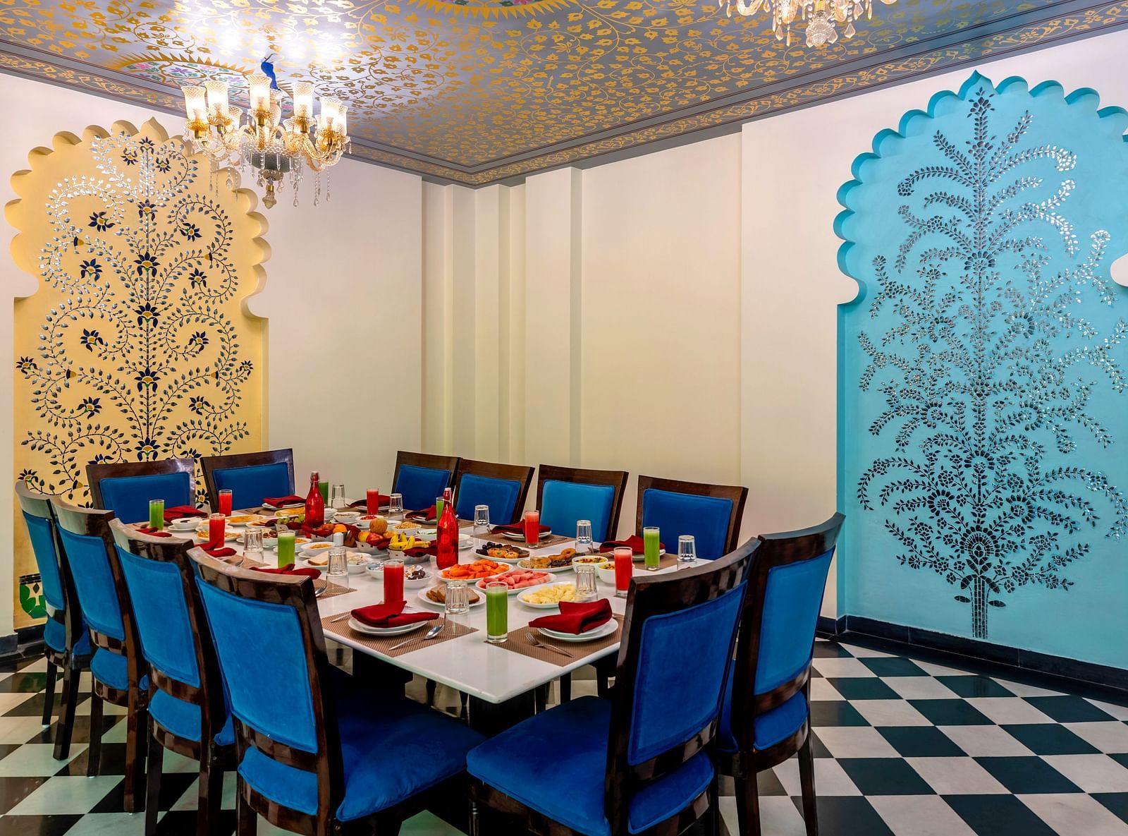 Elegant private dining room with royal blue chairs, carved wall panels in blue and gold, and a crystal chandelier.