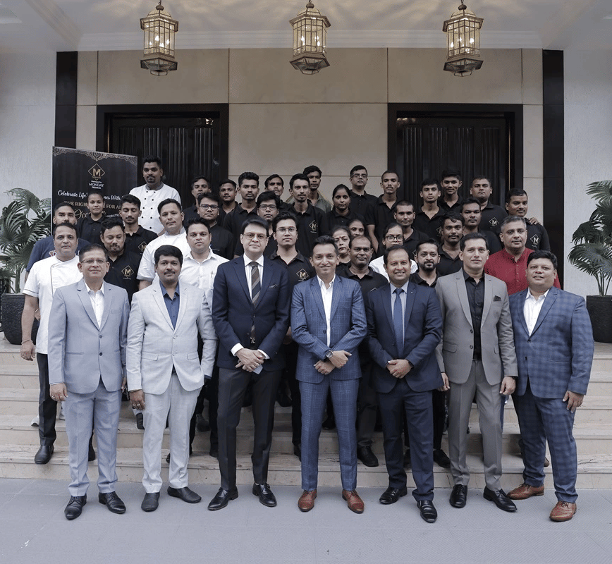 A group of people dressed in business formals gathered together in front of a hotel building.