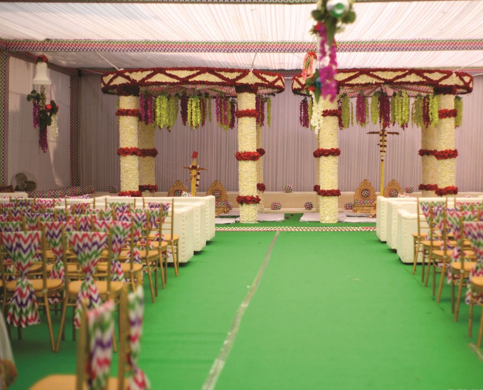 Stage setup for a wedding in a decorated banquet space with a central aisle and chairs on either side | Gemini Continental