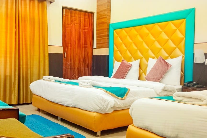 Triple Bed deluxe room with blue and white bed covers at Hotel Panchvati Inn, Joshimath