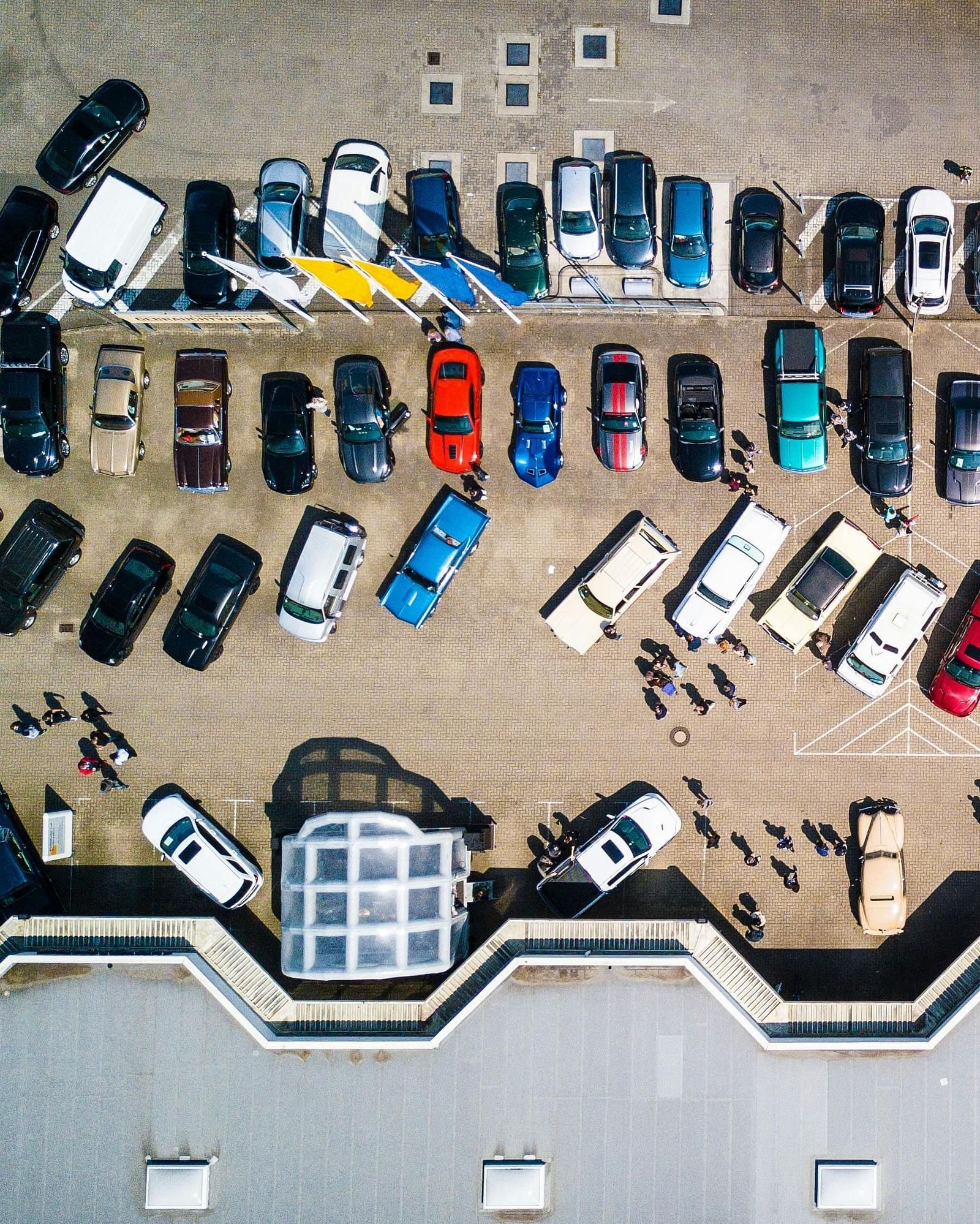A wide angle shot from above of parking lot where several cars are parked.