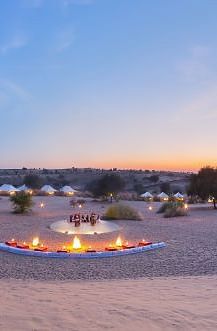 A luxury desert tent with an extended canopy stands amid a dry landscape with sparse trees, under a clear sky - MANVAR Resort & Desert Camp